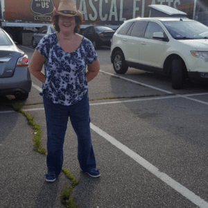 woman in cowboy hat, smiling in front of rascal flatts semi truck