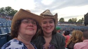 woman and daughter in cowboy hats, smiling during concert