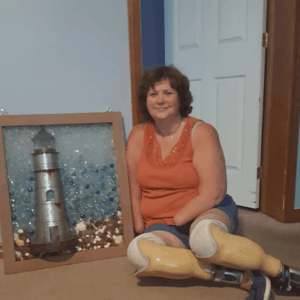 quad amputee sits on floor by Lighthouse in a framed vintage window, colored glass