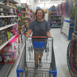 Quadruple amputee smiling while pushing grocery cart in walmart.