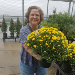Amputee woman smiling while holding yellow mums