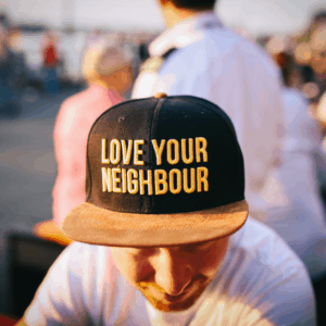 man looking down wearing a love your neighbor ball cap, ideas to pay it forward