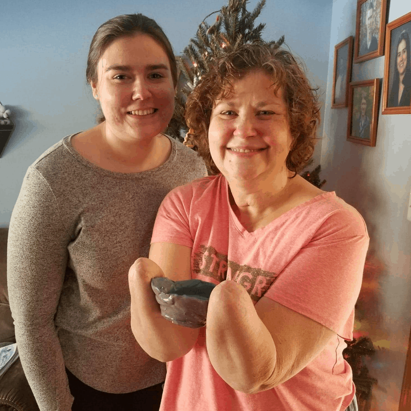 Daughter with amputee mother holding clay bowl