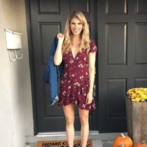 smiling blonde woman in red dress, standing in front of black door